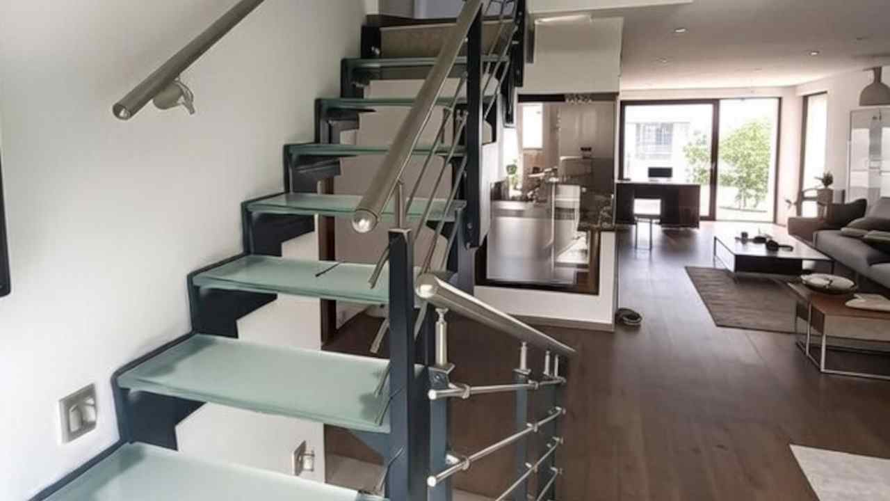 Interiérové schodište s bočnicí z vypalovaného plechu se skleněnými stupni a zábralím z nerezu, konstrukce vbervě antracit